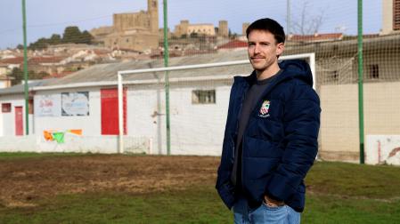 El capitán del Artajonés, David Echeverría, posa en el campo de fútbol con el cerco al fondo.