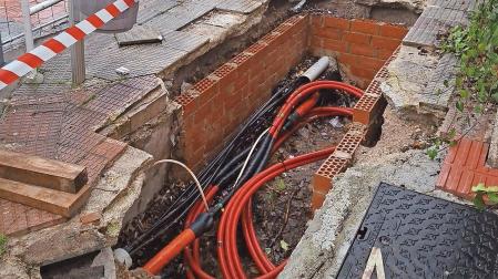 Vista del cableado visible en la zanja abierta en la calle del bloque de viviendas. Al fondo, la avenida Eulza