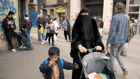 Una mujer con burka camina por una calle del barrio de El Raval de Barcelona