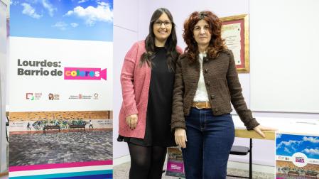 De izda. a dcha.: Claudia Hierro Rodríguez (responsable del Centro Lasa) y Eva Gurría Marco (directora de Políticas Migratorias del Gobierno de Navarra), con el cartel del proyecto ‘Lourdes: Barrio de Colores’