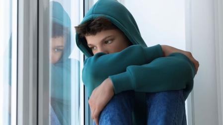 Un adolescente pensativo mirando por la ventana