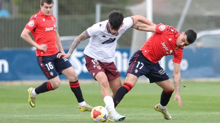 Roberto Arroyo pugna por el balón con Rubén López en presencia de Miguel Auría