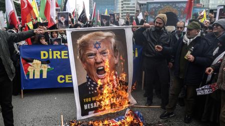 Manifestantes queman una pancarta con el rostro del presidente estadounidense Donald Trump, en una protesta contra los ataques en Estambul
