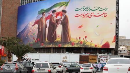 Los coches circulan junto a un enorme mural que muestra a los difuntos líderes supremos iraníes, el ayatolá Ruhollah Jomeini (izq.), el ayatolá Alí Jamenei (centro), y al nuevo líder supremo, el ayatolá Mojtaba Jamenei (der.), en Teherán