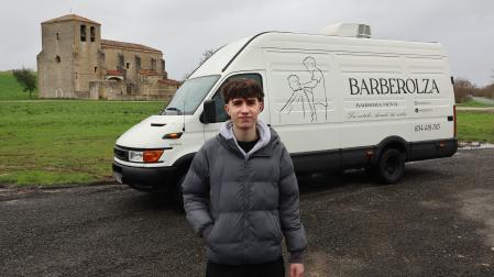 Ion Olza posa delante de la furgoneta ya rotulada y convertida en barbería móvil. Detrás la iglesia de su pueblo, Asiáin