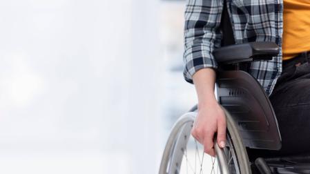 Una persona con discapacidad se apoya en su silla de ruedas