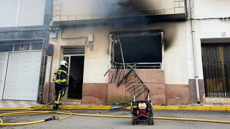 Un bombero realiza las labores de remate de la extinción del fuego en la vivienda afectada