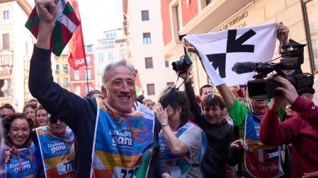 El alcalde Joseba Asiron porta el testigo en el kilómetro financiado por el Ayuntamiento de Pamplona. Tras él, una pancarta de apoyo a los presos de ETA.