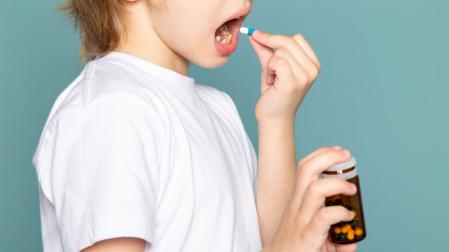 Un niño se toma una pastilla de antibiótico