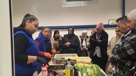 Ely y su compañera cocinan verdura de Navarra para las personas migrantes.