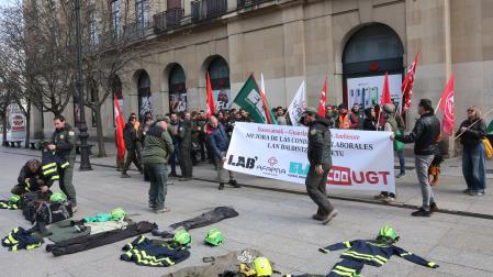 Los participantes en la concentración, con prendas de trabajo en el suelo y delante del Palacio de Navarra