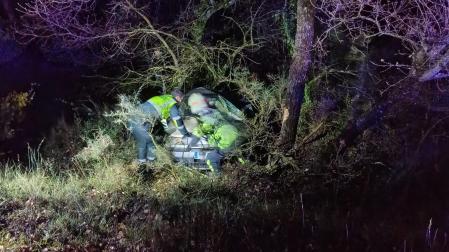 Agentes de la Guardia Civil, junto al vehículo siniestrado, que cayó por un talud