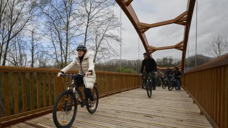 Un grupo de asistentes a la visita oficial de este martes atraviesa en bici la pasarela de Lekaroz.
