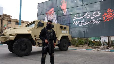 Un miembro de las fuerzas de seguridad iraníes monta guardia junto a una pancarta en honor al exlíder supremo iraní Ali Jamenei, en Teherán