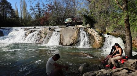 Tres personas se refrescan en la presa de Huarte e estos días de calor.