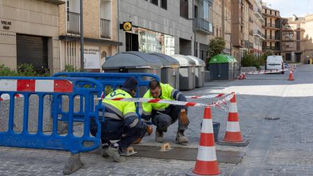 Dos operarios reparan los daños aparecidos en el pavimento de la calle Muro de Tudela
