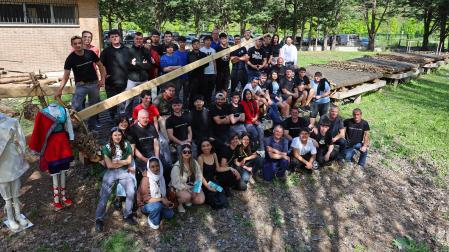 Alumnado, profesorado, almadieros y colaboradores, junto a la almadía que luce en el patio del C.I. Donibane de Pamplona, y el nuevo traje de almadiera