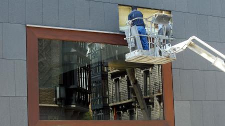 Operarios arreglando un grupo de placas de granito que recubren la fachada del edificio de Baluarte