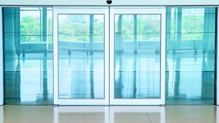 Imagen genérica de una puerta automática con dos paneles de cristal y un sensor que detecta la aproximación