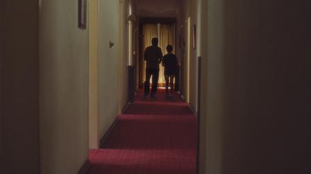 Fotograma de 'Una película de miedo' con padre e hijo por uno de los pasillos del hotel abandonado