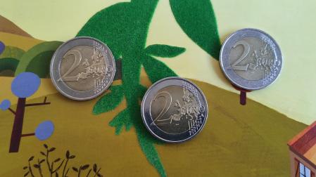 Tres monedas de 2 euros sobre un cuento infantil