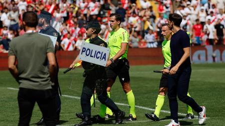 El arbitro José Luis Guzmán Mansilla (c) sale escoltado por la policiía mientras escucha las quejas del entrenador del Rayo Vallecano Íñigo Pérez (d) tras el partido de LaLiga entre el Rayo Vallecano y la Real Sociedad