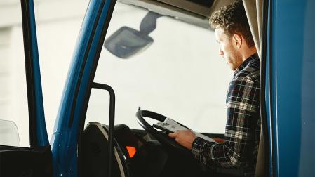 Un camionero consulta documentación a bordo de la cabina de su vehículo