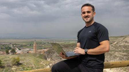 Alex Bienzobas Asensio, coach online, sujetando un portátil con Arguedas de fondo