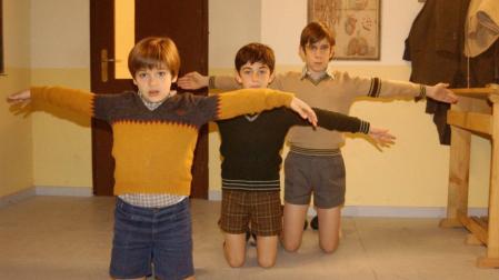 Carlos Alcántara (Ricardo Gómez) y sus amigos Josete (Santiago Crespo) y Luis (Manuel Dios), castigados de rodillas y con los brazos en cruz, en la serie 'Cuéntame cómo pasó' de TVE.
