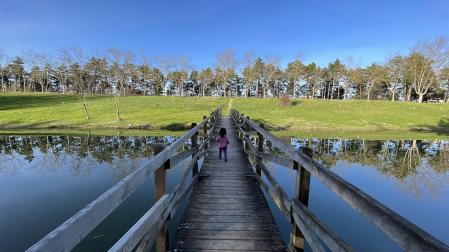 Una niña atraviesa el puente de madera de la balsa de Ardoi