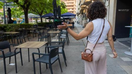 Una mujer intenta dispersar los mosquitos en la terraza vacía del bar Winter, en el paseo de Invierno de Tudela