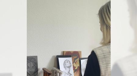 Una de las residentes en el cuarto que ocupa, lleno de las pinturas que ha hecho