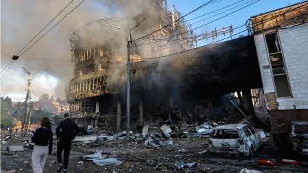 Varias personas caminan entre los escombros en el lugar donde un ataque ruso ha alcanzado un centro comercial en Kiev