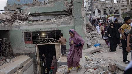 Refugiados palestinos entre los escombros de una localidad cercana a Gaza tras un bombardeo