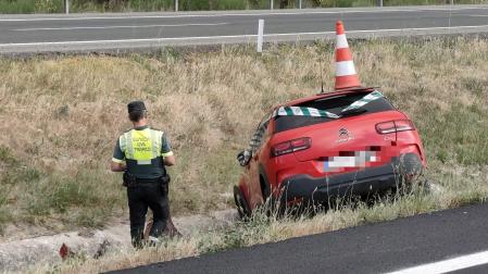 Un agente de la Guardia Civil, junto a uno de los vehículos accidentados