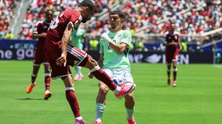 El catarí Boualem Khoukhi, autor del tanto del empate en el descuento, despeja ante la presión del suizo Zeki Amdouni