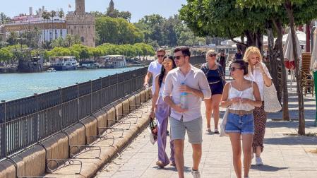 Un joven cruza el puente de San Telmo de Sevilla con una botella de agua