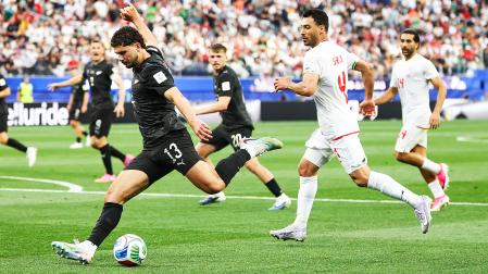 Liberato Cacace, de Nueva Zelanda, busca el disparo a portería entre rivales de Irán durante el encuentro del Mundial