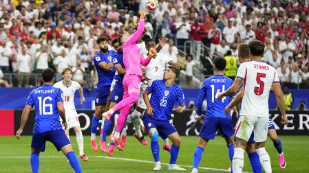 El meta croata Dominik Livakovic, que realizó un buen encuentro pese a la derrota, despeja de puños un envío al área de Inglaterra