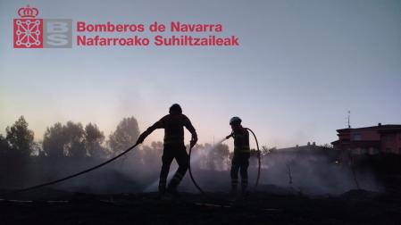 Dos bomberos trabajan en el incendio que ha afectado a un talud cerca del casco urbano de Lerin
