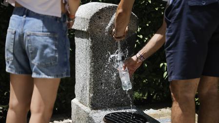 Dos personas cogen agua en una fuente para paliar los efectos del calor
