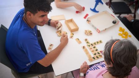 El escolapio Pedro Díaz, de la Fundación Itaka, juega a un juego de mesa con una usuaria