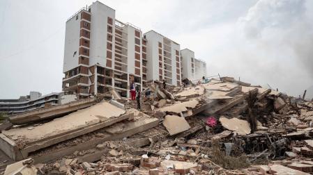 Personas caminan por los escombros de edificios afectados por los terremotos que se han producido este jueves, en La Guaira (Venezuela)
