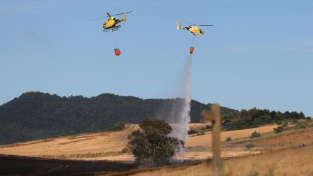 Dos helicópteros trabajando sobre un incendio declarado en un campo de cereal de Badostain