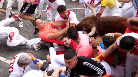 Caído, Jordan Gellida Martínez estira los brazos ante el impacto de un corredor y el toro 'Juncoso'.