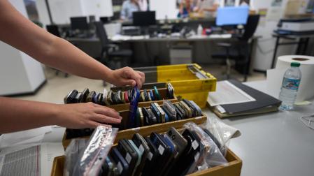 Una persona revisa una caja con teléfonos en la oficina de objetos perdidos de Pamplona, este 16 de julio.