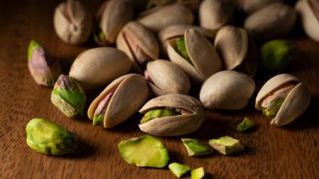 Close-up of a pistachio placed against a wood grain background