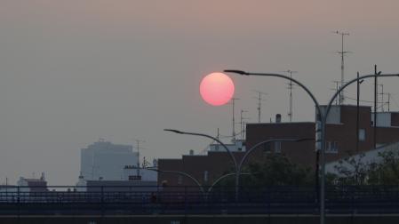 Vista del amanecer desde Plaza Elíptica con un manto de ceniza sobre Madrid este sábado debido a los incendios forestales que asolan la comunidad