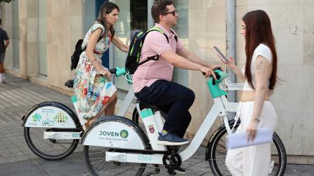 Imagen de archivo del pasado verano con dos personas circulando por Pamplona con las bicicletas del servicio municipal de alquiler