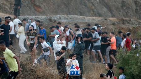Imagen de personas escapando este jueves de las fuerzas antidisturbios marroquies que han desalojado a las masas que se encontraban cerca de la frontera con Ceuta.